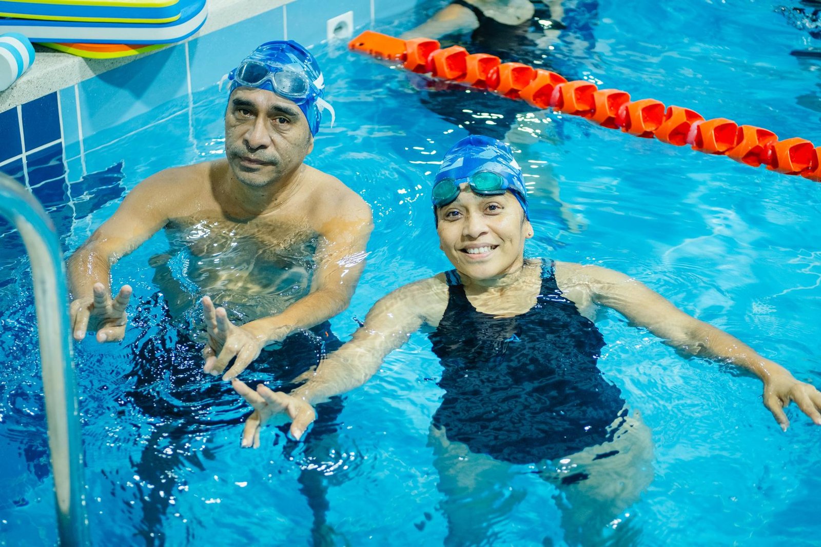 Dos alumnos adultos conversando en el borde de la piscina